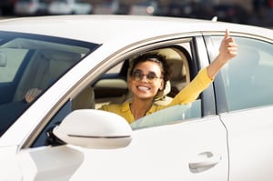 smiling woman in an car during the summer in white car with yellow shirt