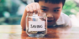 child_putting_money_savings_jar