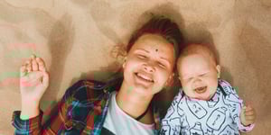 mom and baby laughing in the sand