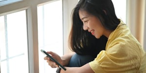 person-smiling-at-phone-by-window