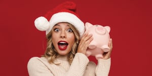 person holding a piggy bank with a Santa hat